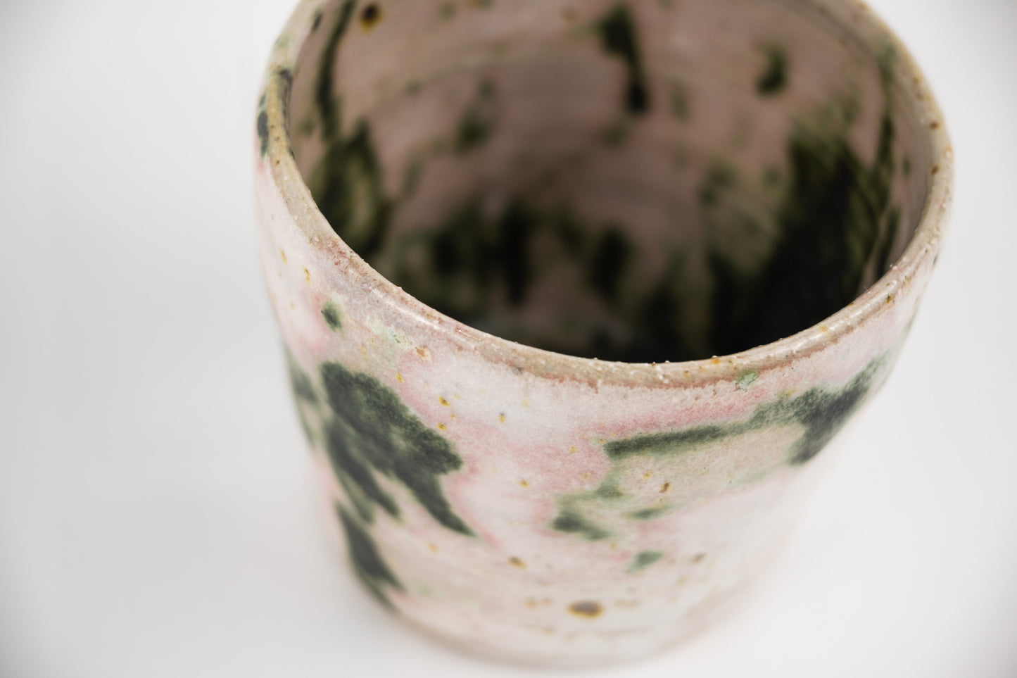 White glaze featuring splashed oxide mug with pink and green hues